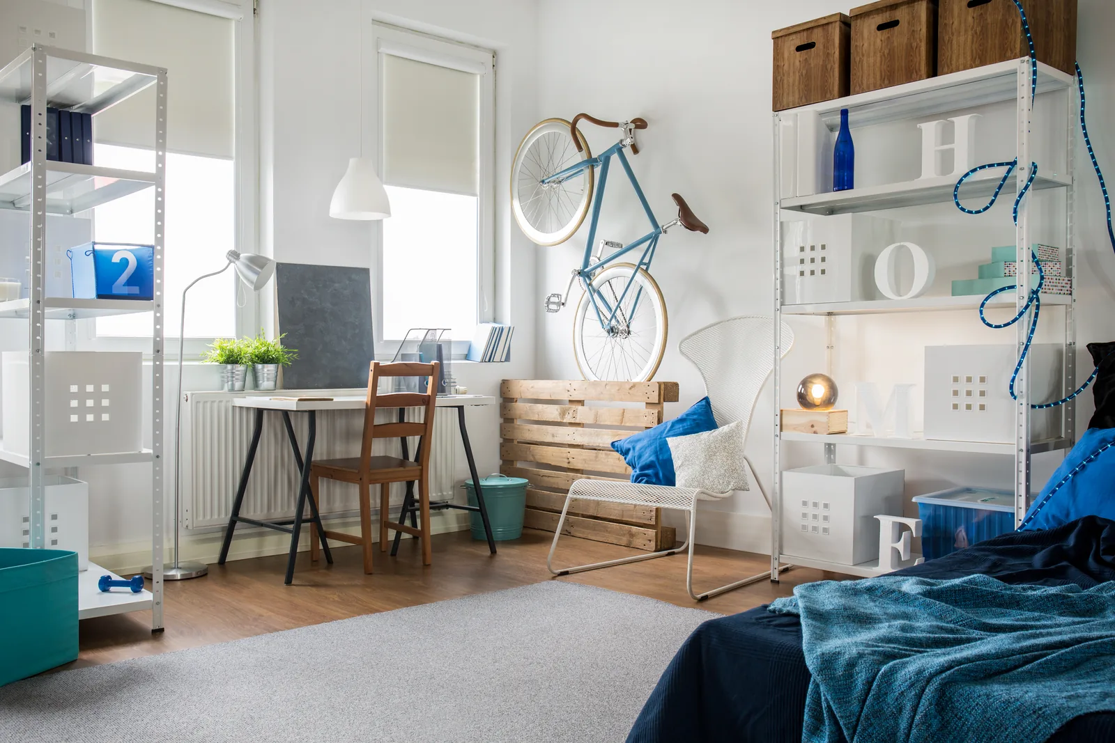 Helles Zimmer mit Regalen, Schreibtisch und einem Fahrrad an der Wand