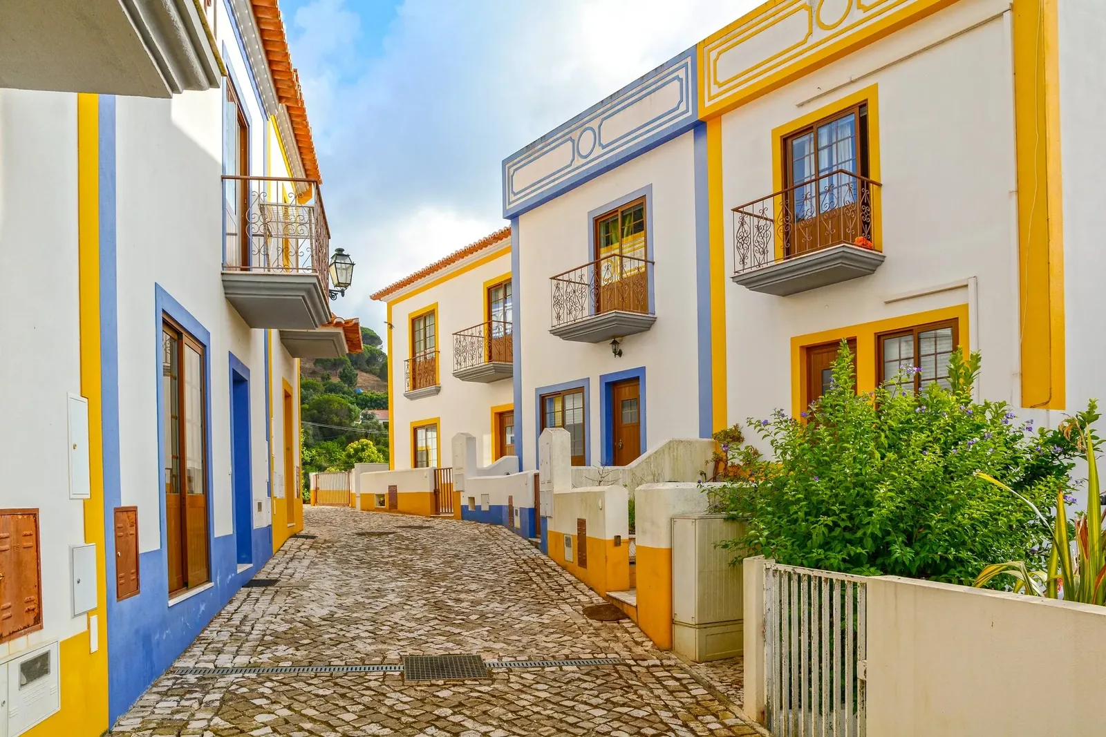 Gepflasterte Gasse mit blau-gelb gefassten Häusern, keine Menschen